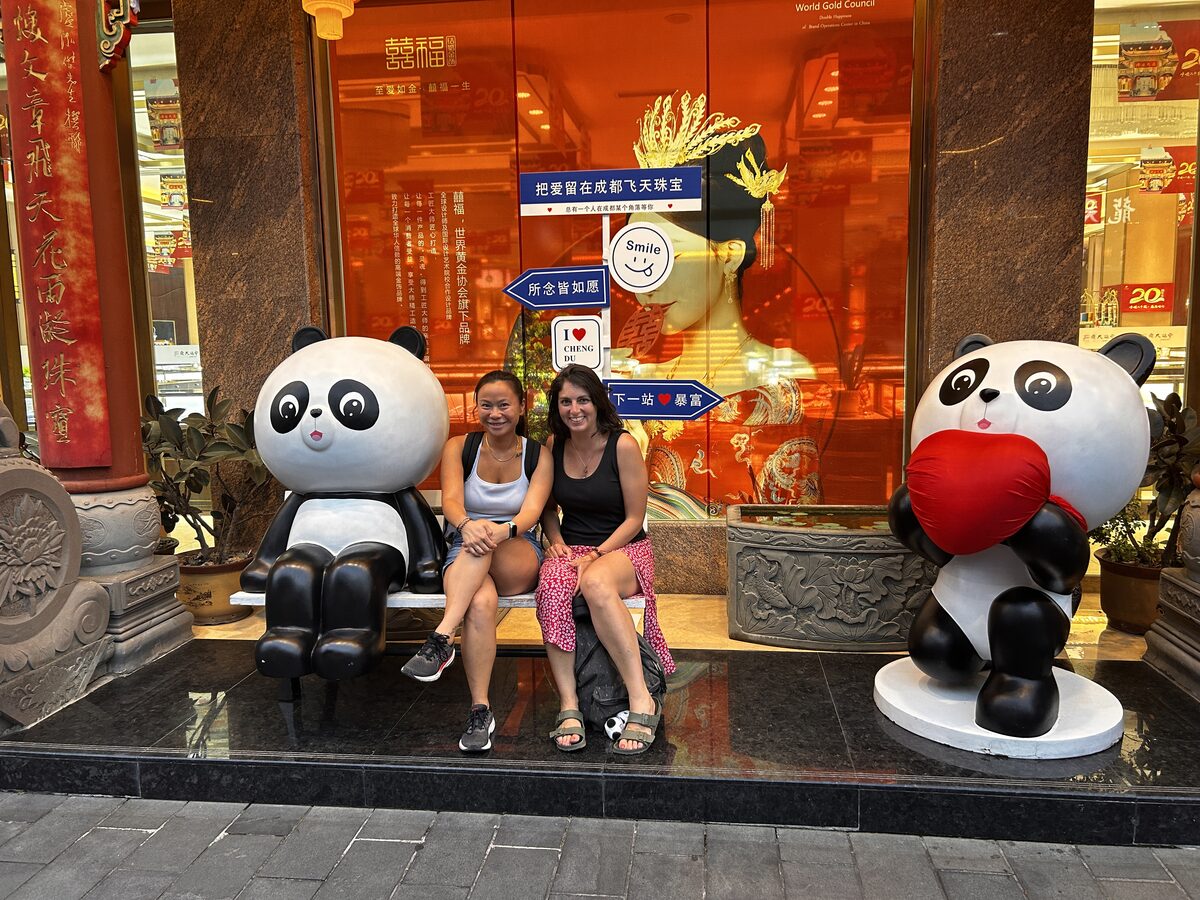 Junto a estatuas de pandas, frente a un centro comercial de lujo